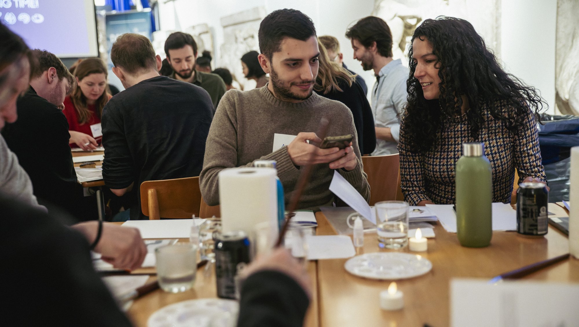 Shows people sitting at tables starting the water colour workshop.