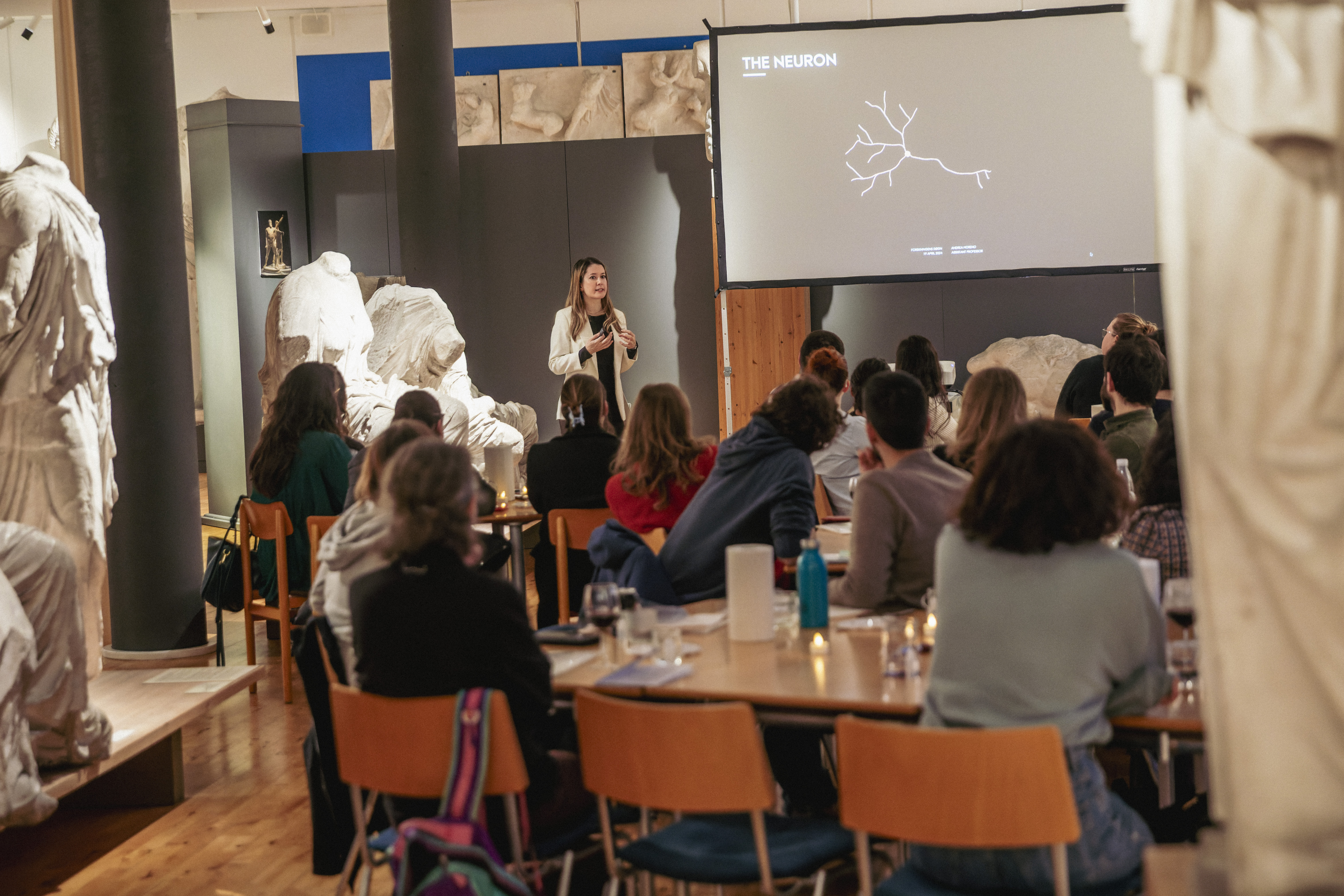 Shows Andrea Moreno giving the scientific presentation and the audience.